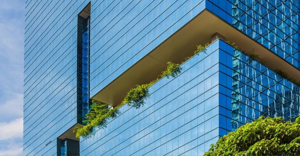 A tall green office building overflowing with plants.