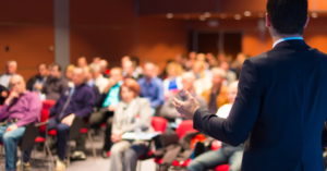 A speaker addressing a large crowd of people.